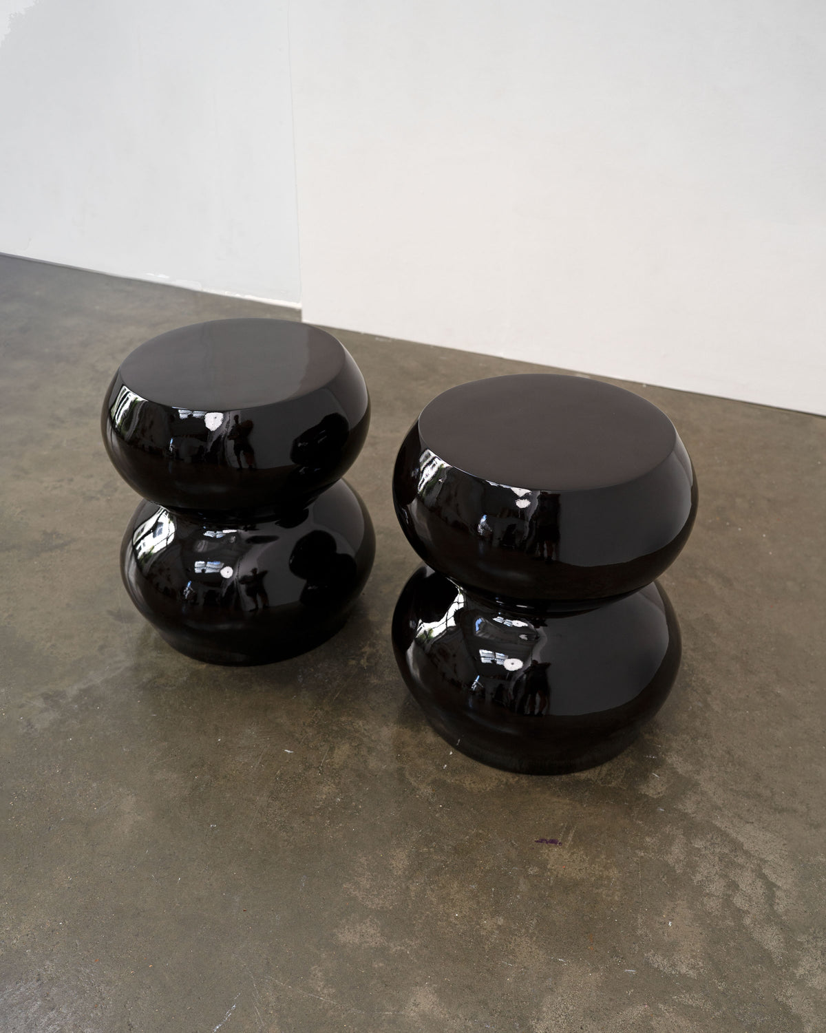 Black lacquered sculptural stools on concrete gallery floor