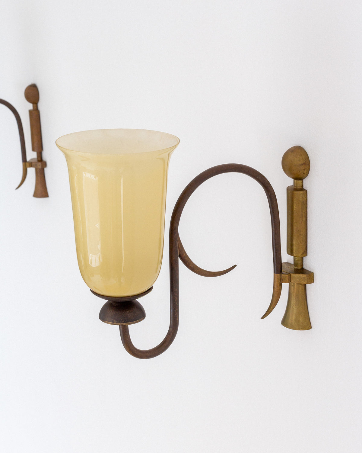 Art Deco wall sconce detail showing brass arm and amber glass shade