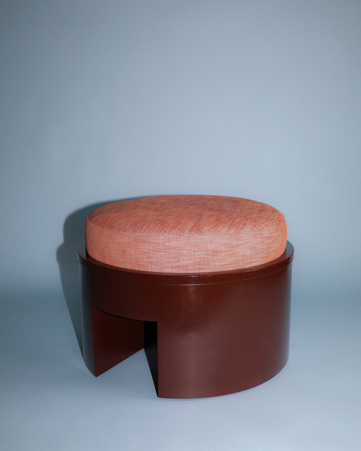 Roan round ottoman with coral upholstery and walnut base detail
