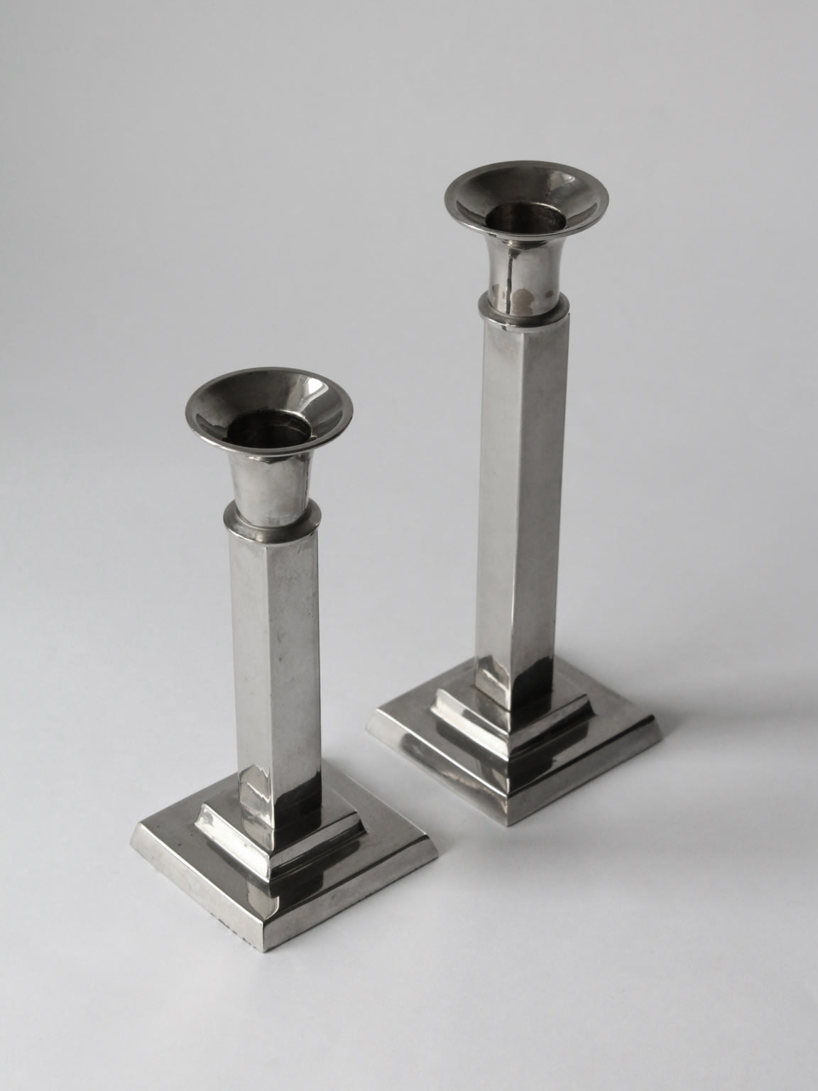 Two Art Deco silver plated candlesticks with stepped square bases