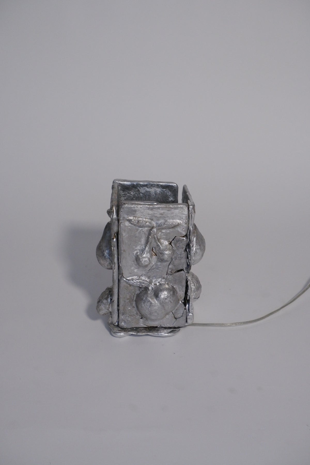 Sculptural silver table lamp with melted metal texture and cord