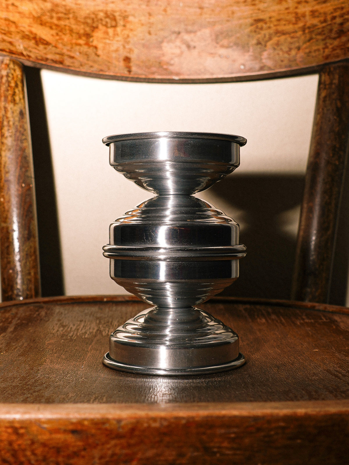 Metal Candle Holders in Polished Aluminum — close-up on wooden chair
