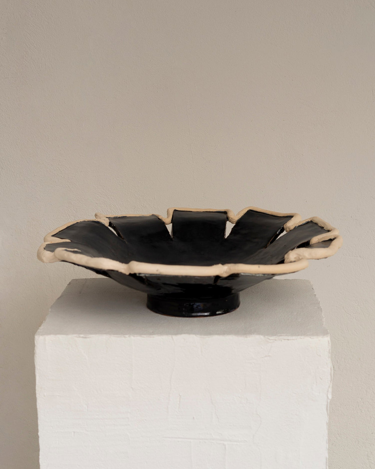 Navy blue ceramic decorative dish with sculptural ruffled edge on pedestal