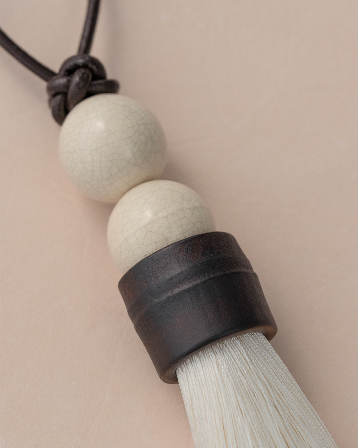 Close-up detail of ceramic beads and dark wood cylinder on tassel