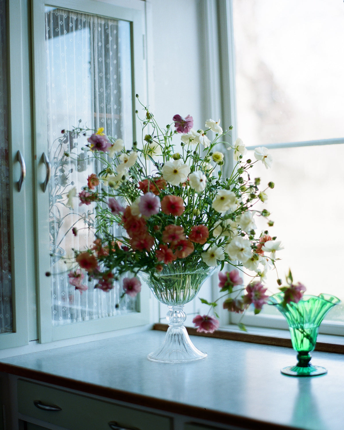 Blixen Vase Large — clear glass vase with floral arrangement in window