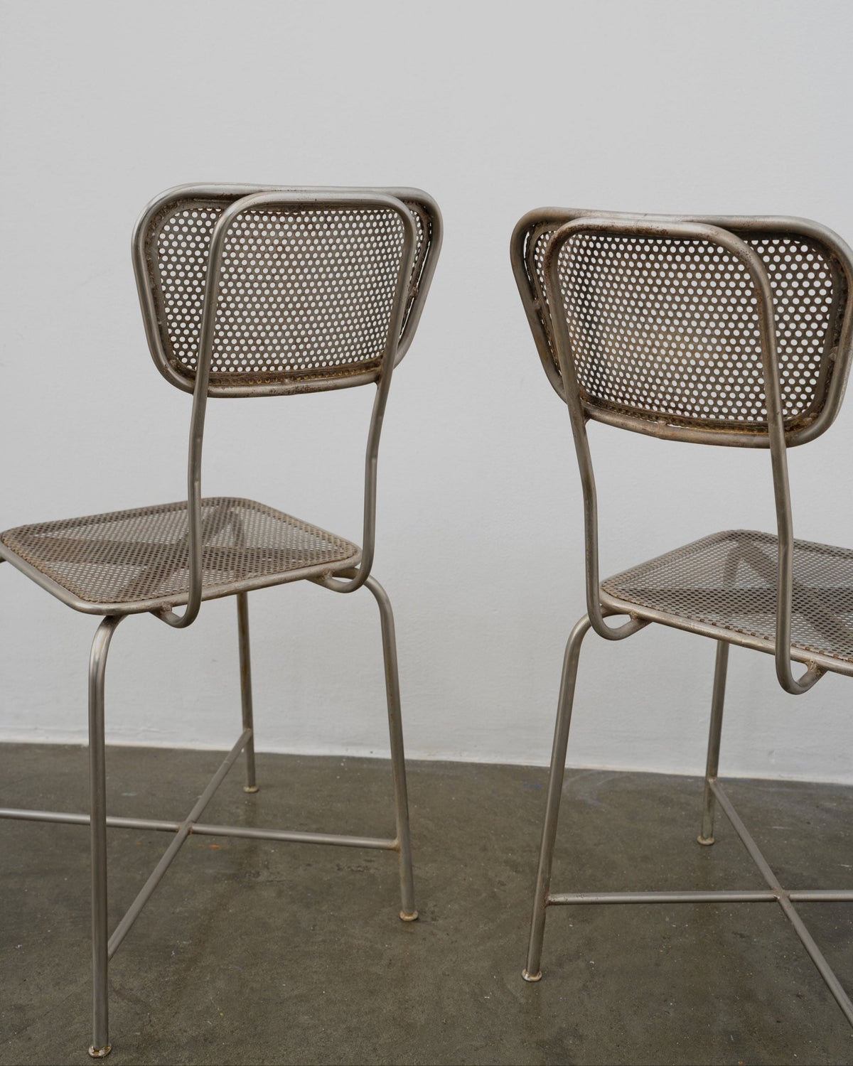 Rear view of vintage perforated metal dining chairs by Tom Bogle