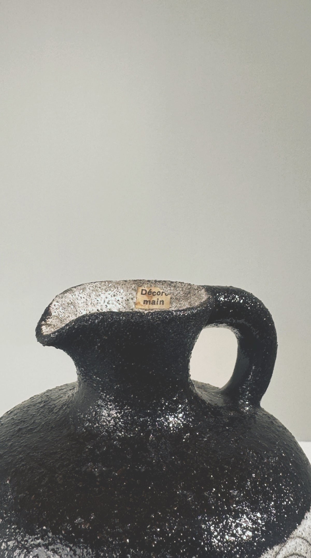 Close-up detail of black textured stoneware pitcher spout and handle