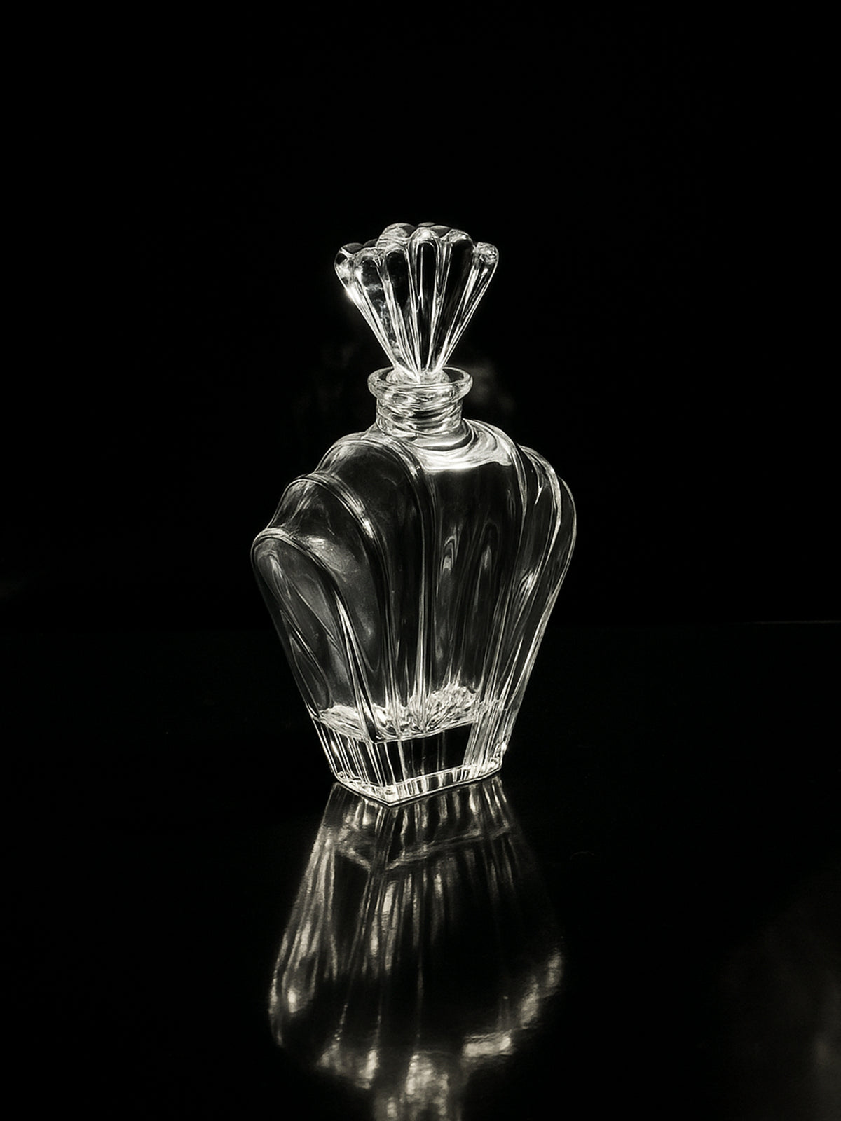 The Italian crystal Glass Art Deco Decanter by Dodo Vintage (1980s) features a sleek design with a fan-shaped stopper, showcased against a black background with light highlighting its curves.