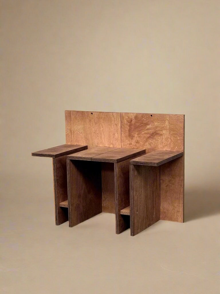 The "Sisto" Versatile Wood Chair by Edoardo Lietti Studio features two attached seats and backs in flat, natural brown plywood, creating a minimalist sculptural look against a plain beige background.