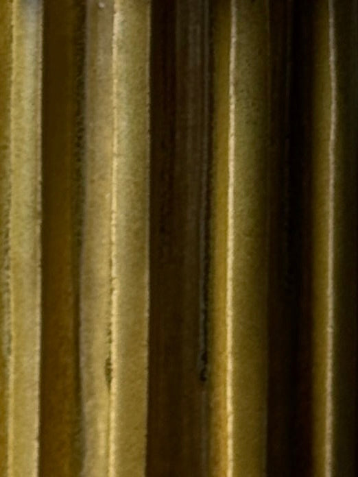 Close-up image of vertical, parallel lines in yellow and brown shades, with lighting that emphasizes the textured grooves, reflecting the design of Vessel No. II by Devin Wilde.