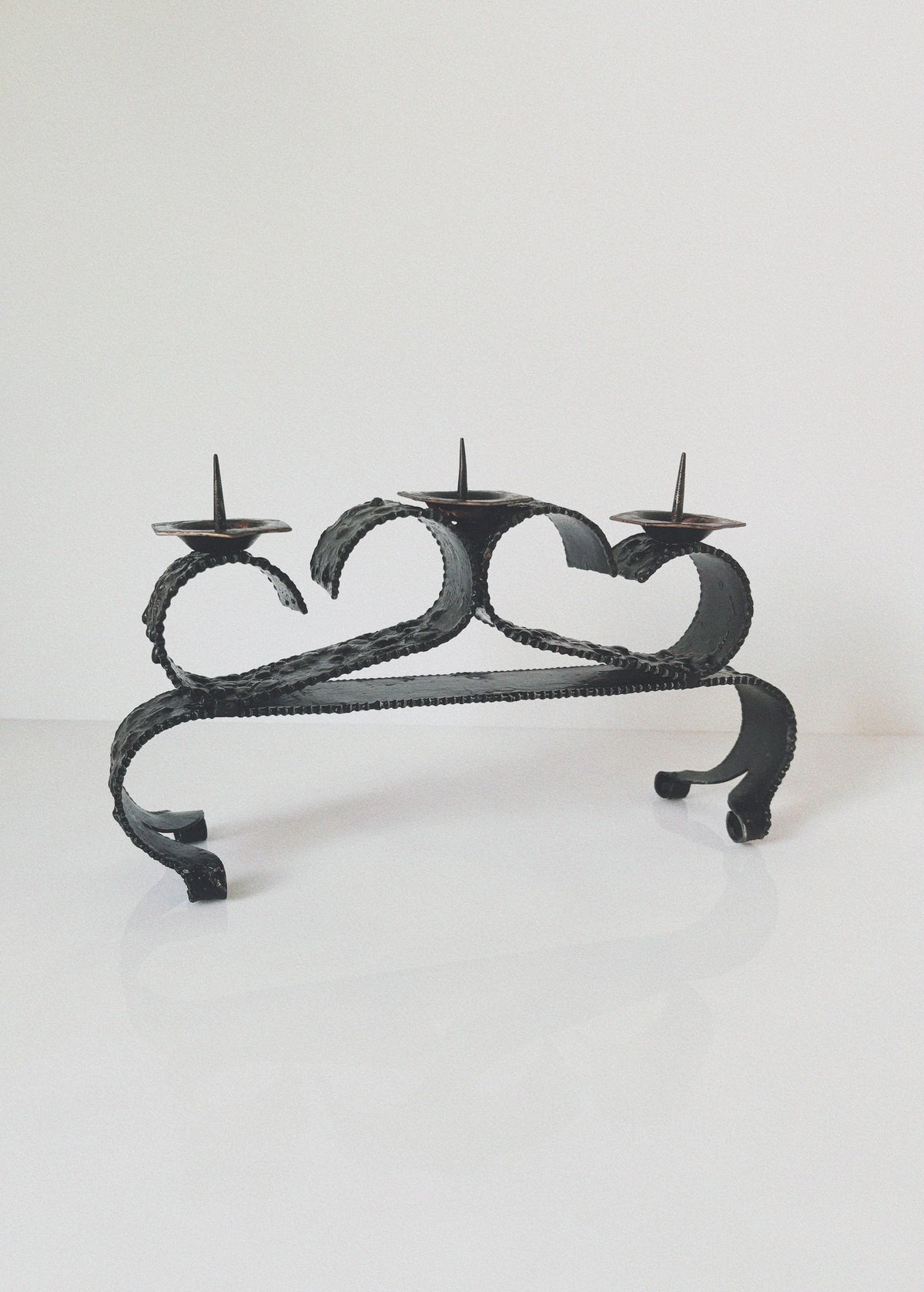 Three-candle wrought iron candleholder with curved serpentine design