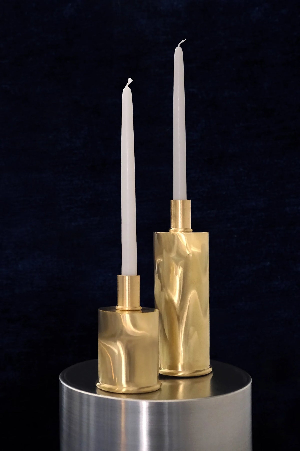 Tall Brushed Brass Candle Holders in Brushed natural brass — side angle on metallic pedestal