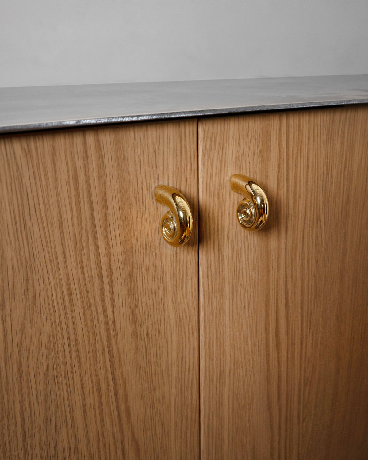 Noelle Knob - Brass — close-up on wooden cabinet doors with brass knobs