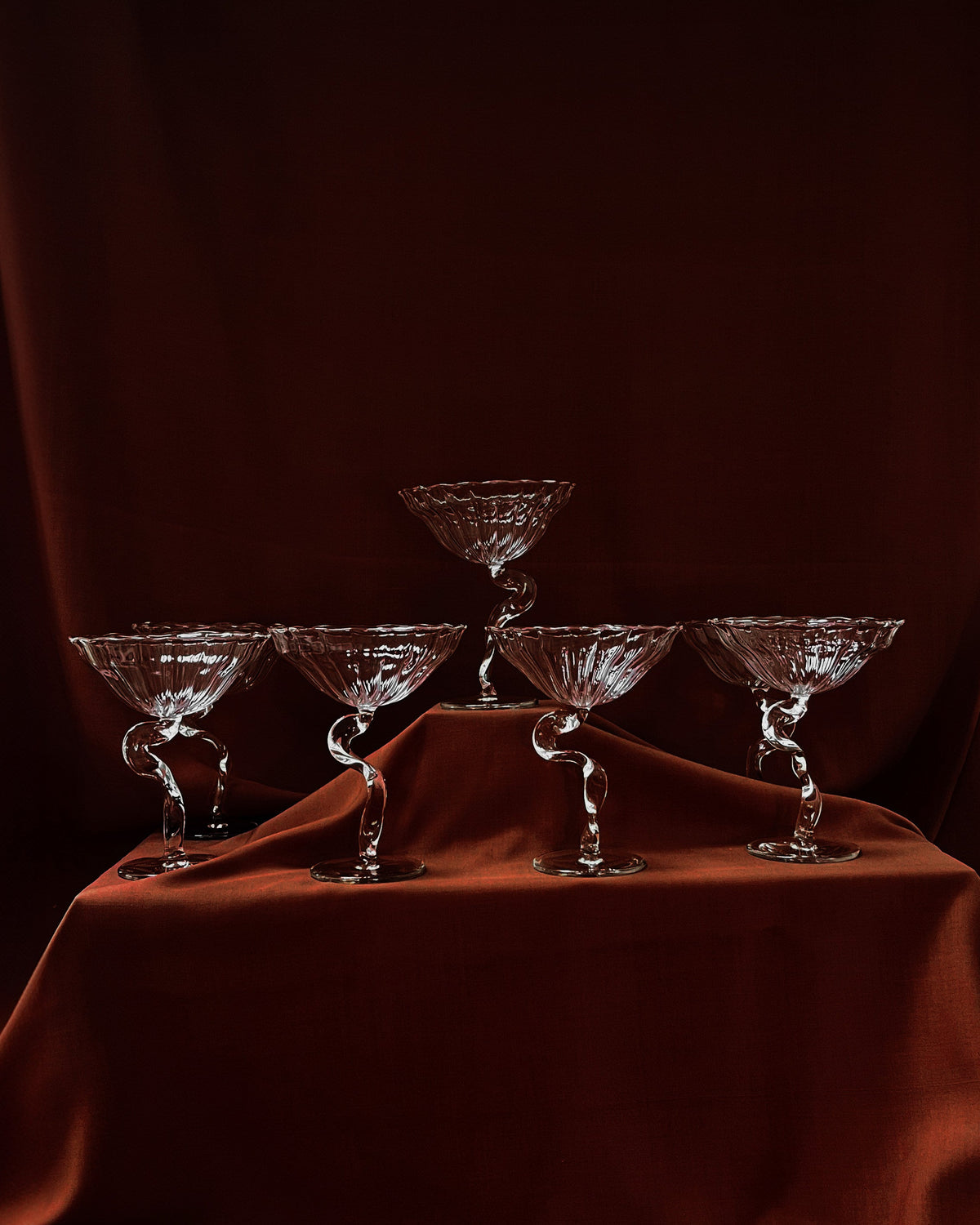 Crystal Ribbon cocktail coupes with twisted stems on burgundy silk