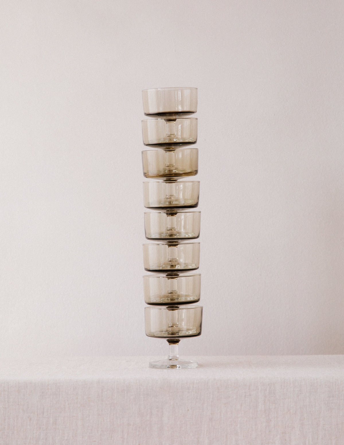 Stack of eight smoked glass champagne coupes arranged vertically