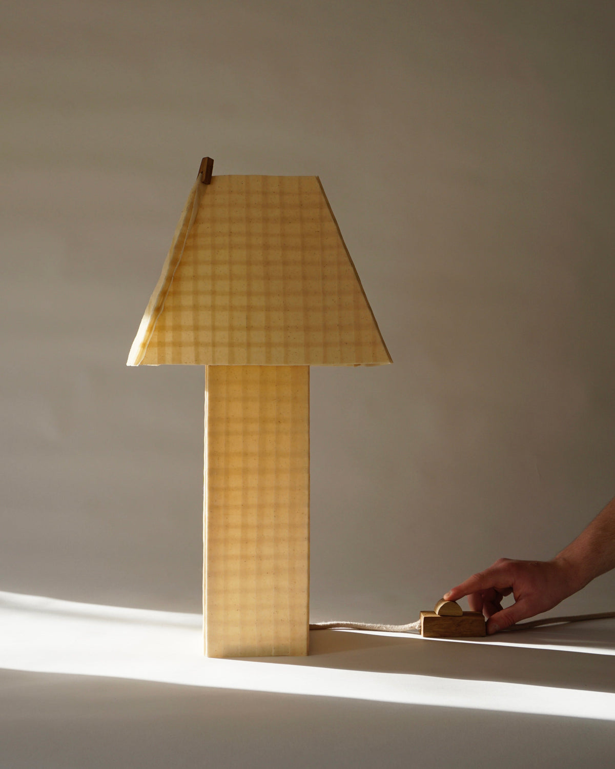 Yellow checkered table lamp with geometric base and hand adjusting dimmer