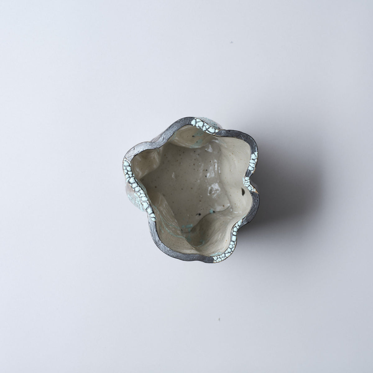 A top-down view of the Astrid Öhman Swirly Vase Brown and Light Blue, a handmade stoneware ceramic vase with an irregular wavy rim and glossy light gray interior, set against a plain white background.