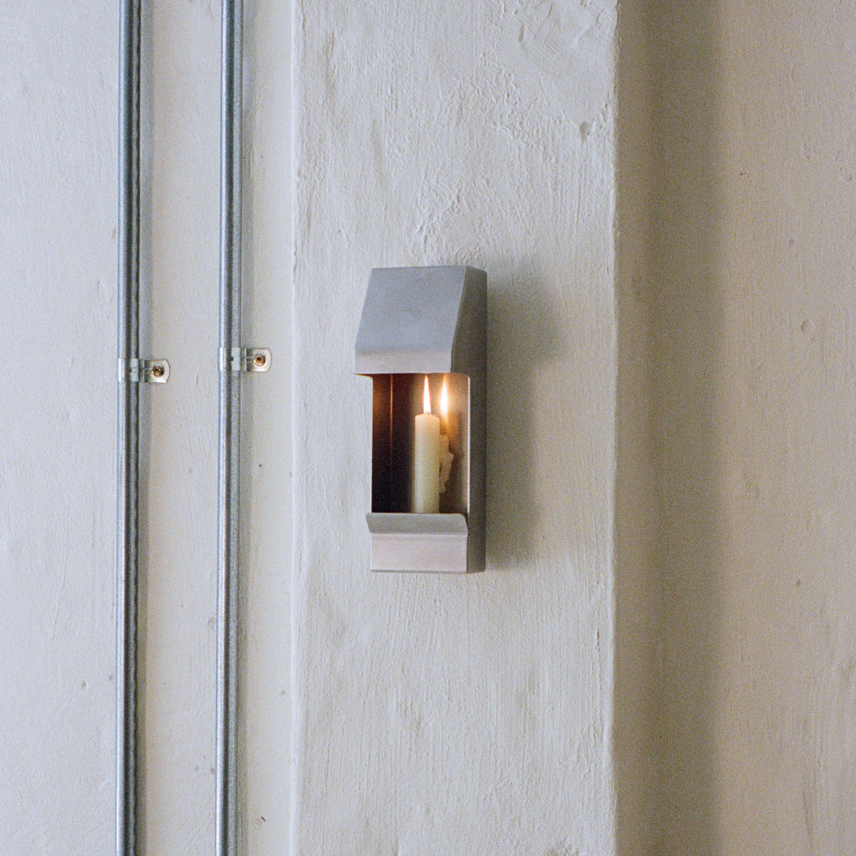 Egress Sconce Candle Holder — wall-mounted with lit candle in modern setting