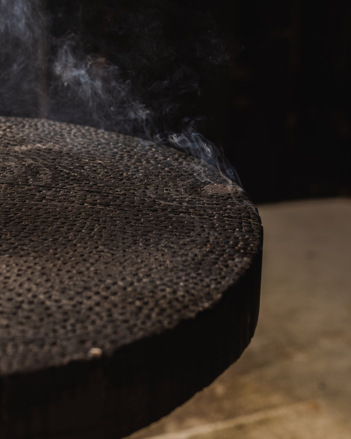 ABORA burnt wood end table with textured surface and visible steam