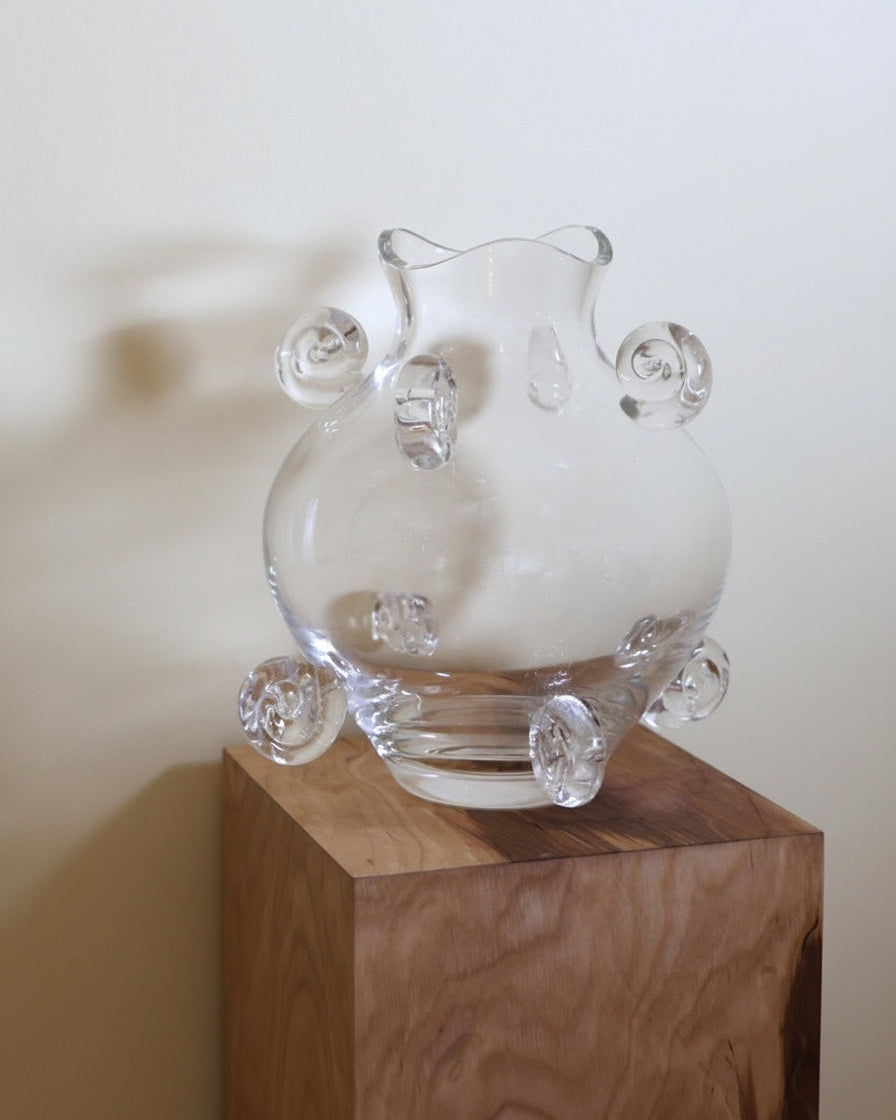 Clear crystal vase with curved handles on wooden display stand