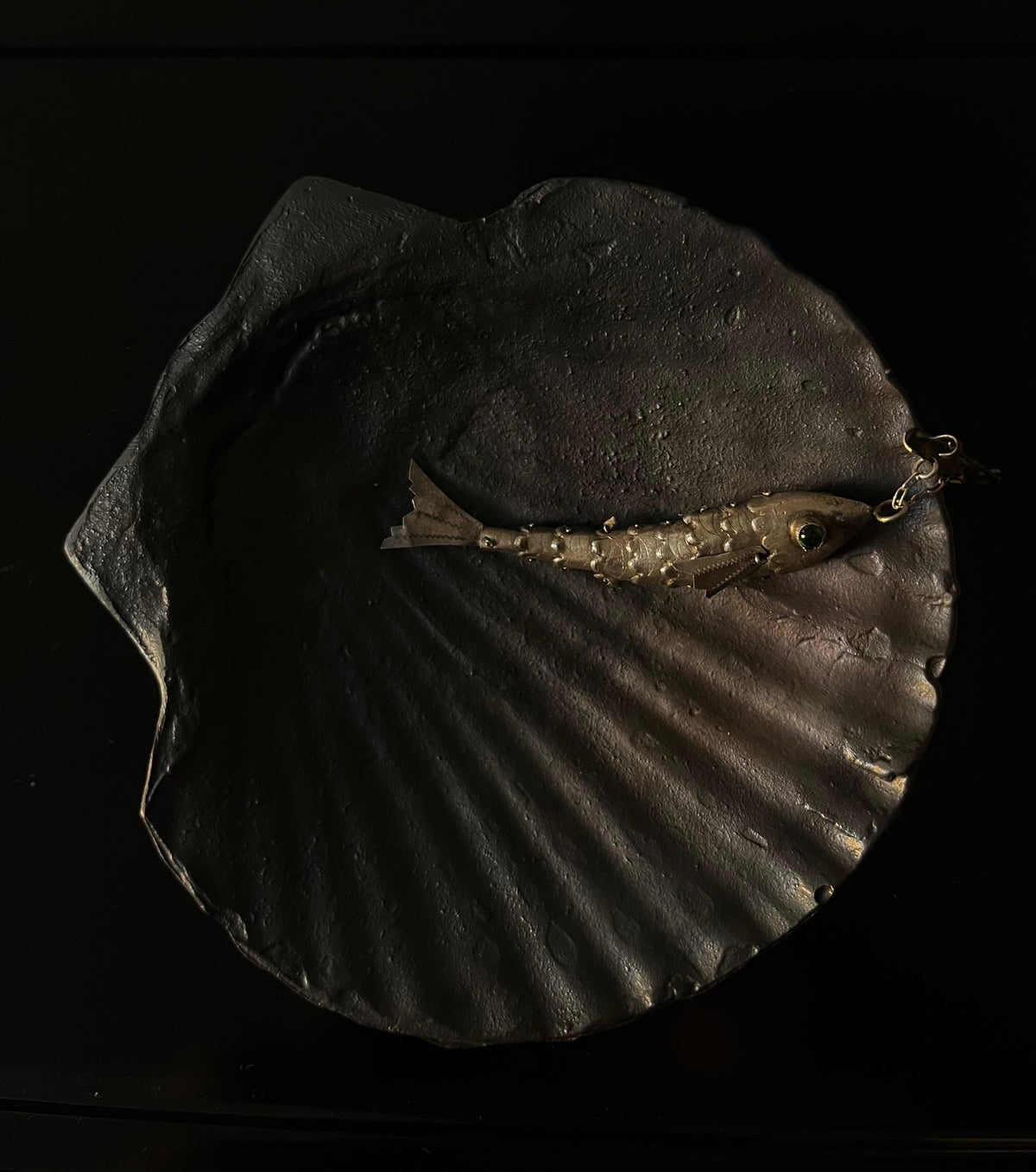 Fossil Shell Plate — side angle showing textured dark surface with fish decoration