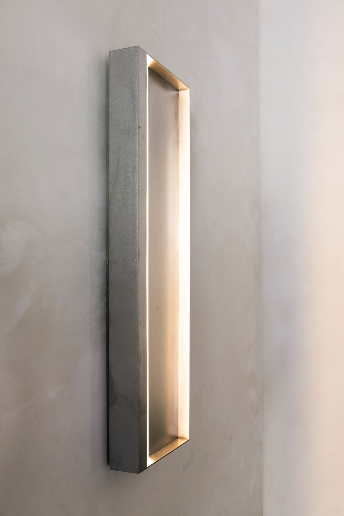 Julie Wall Lamp — side angle showing concrete finish and warm light