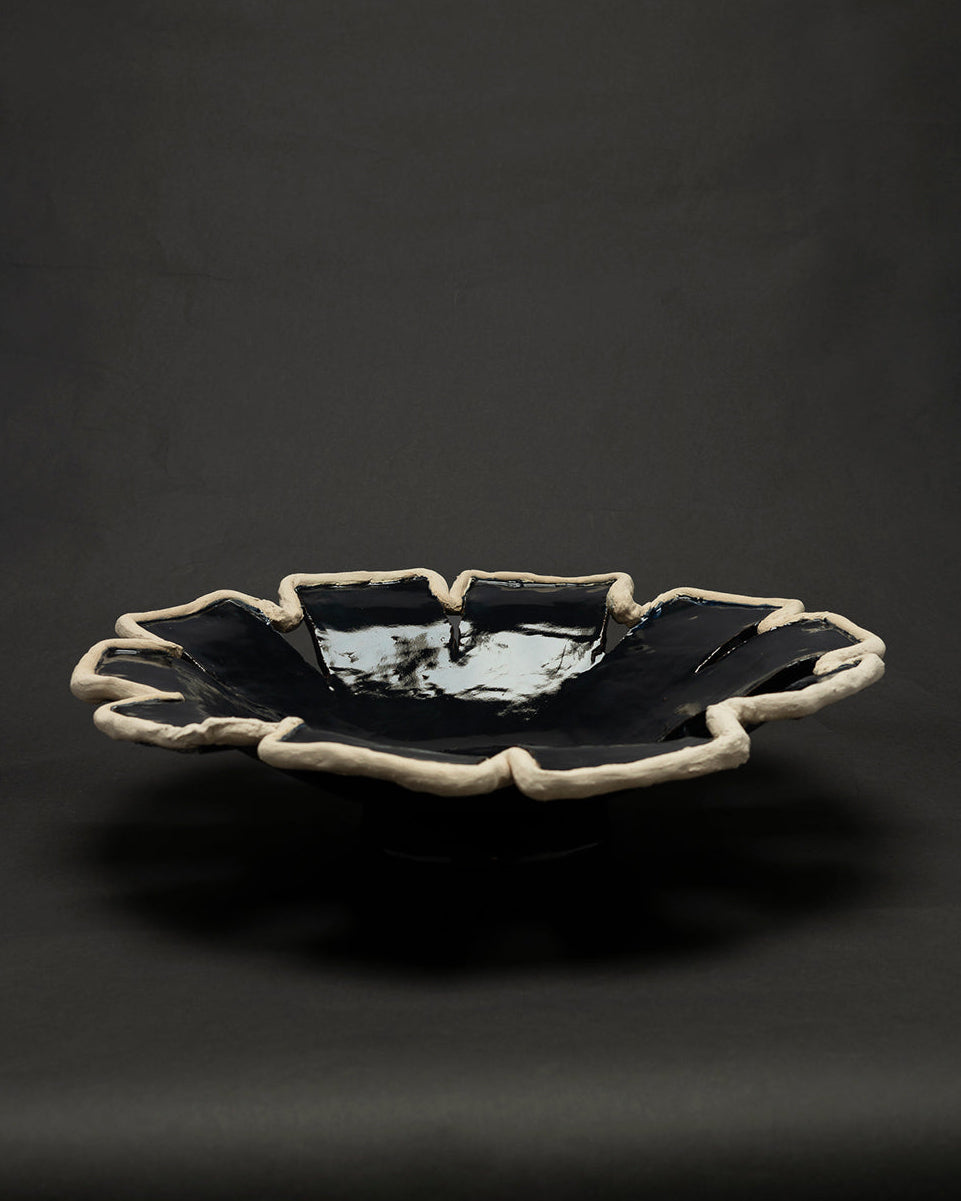 Navy blue ceramic decorative dish with organic white clay rim, profile view