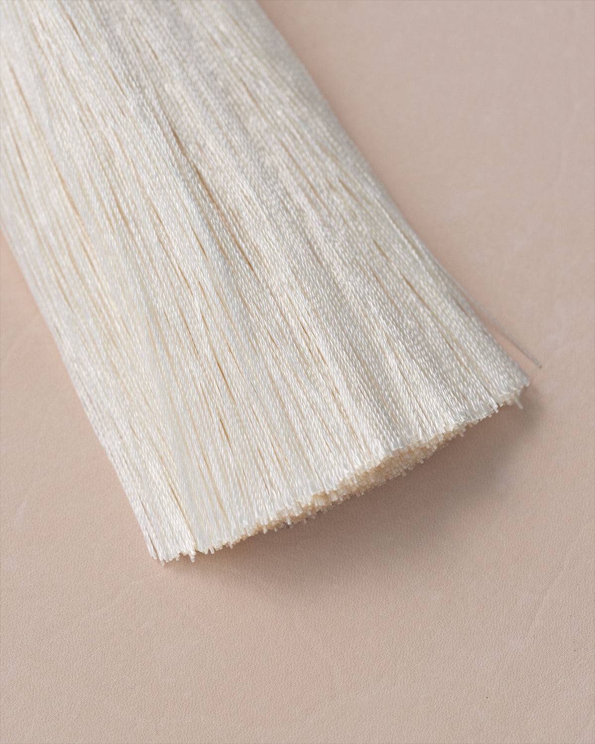 Close-up detail of cream silk tassel fringe with fine fibers