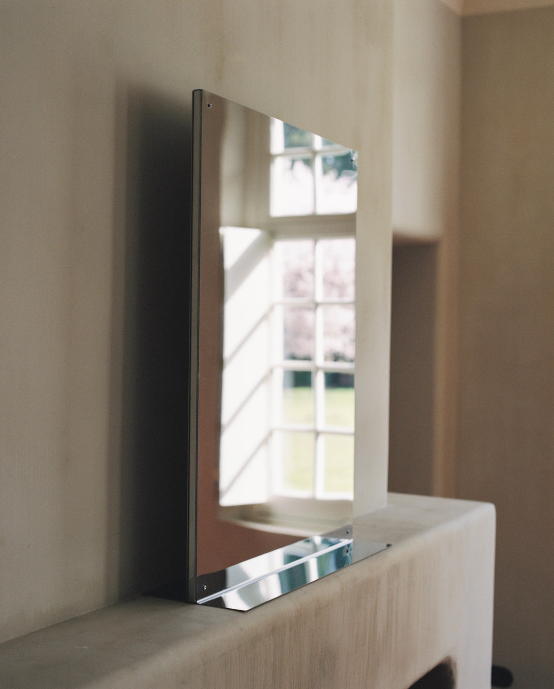 Large rectangular flat mirror with chrome frame on wooden surface