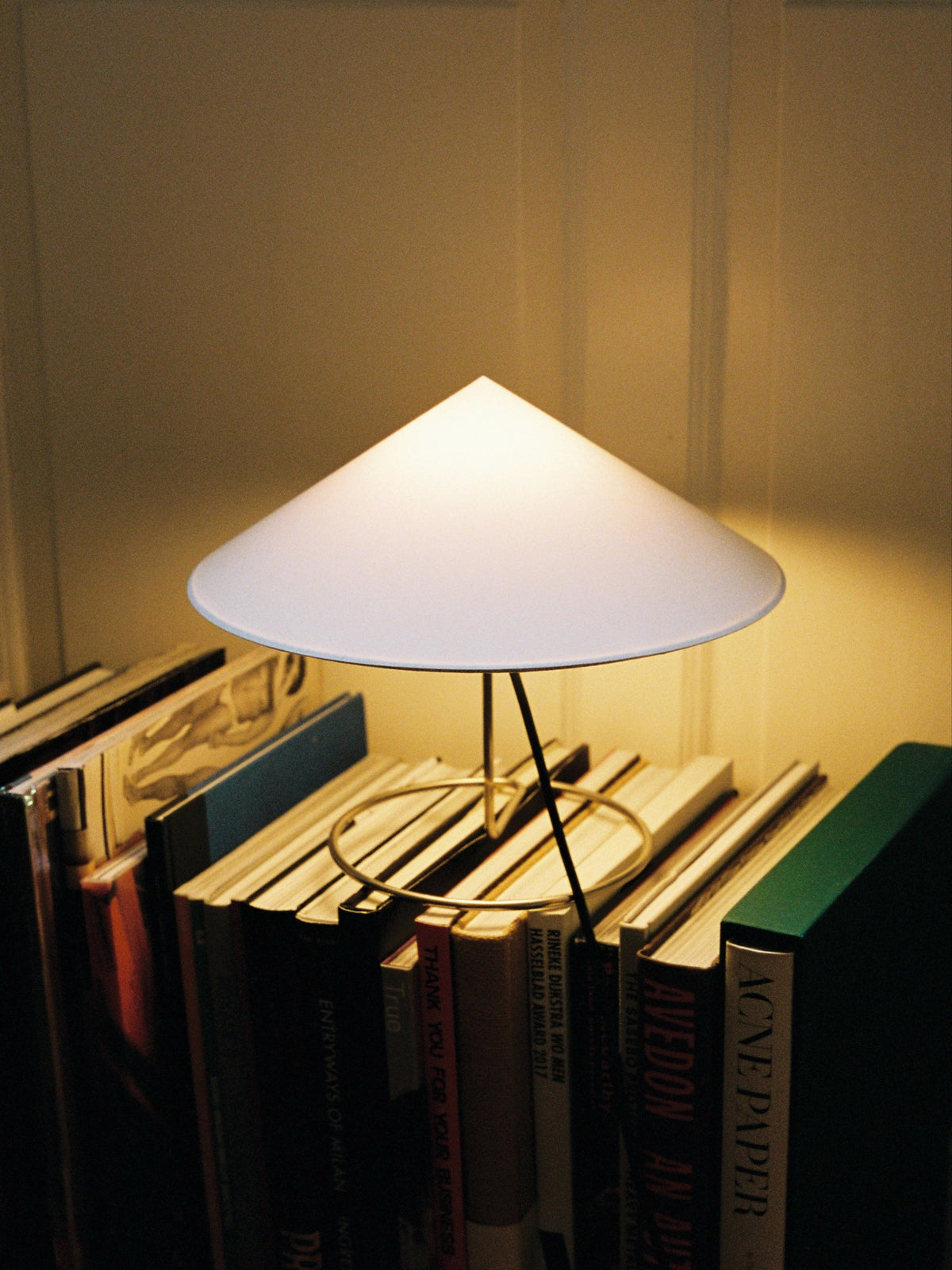 Douli Table Lamp — white conical shade above stacked books