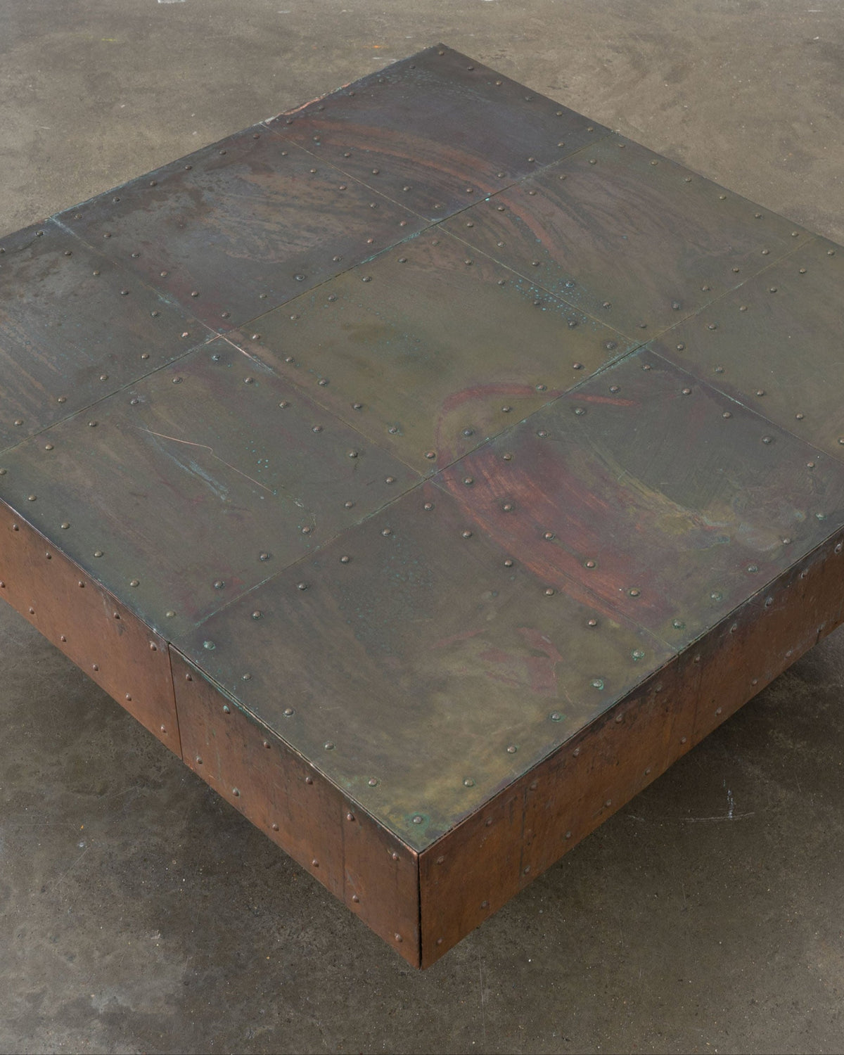 Copper coffee table top detail showing patina and riveted construction