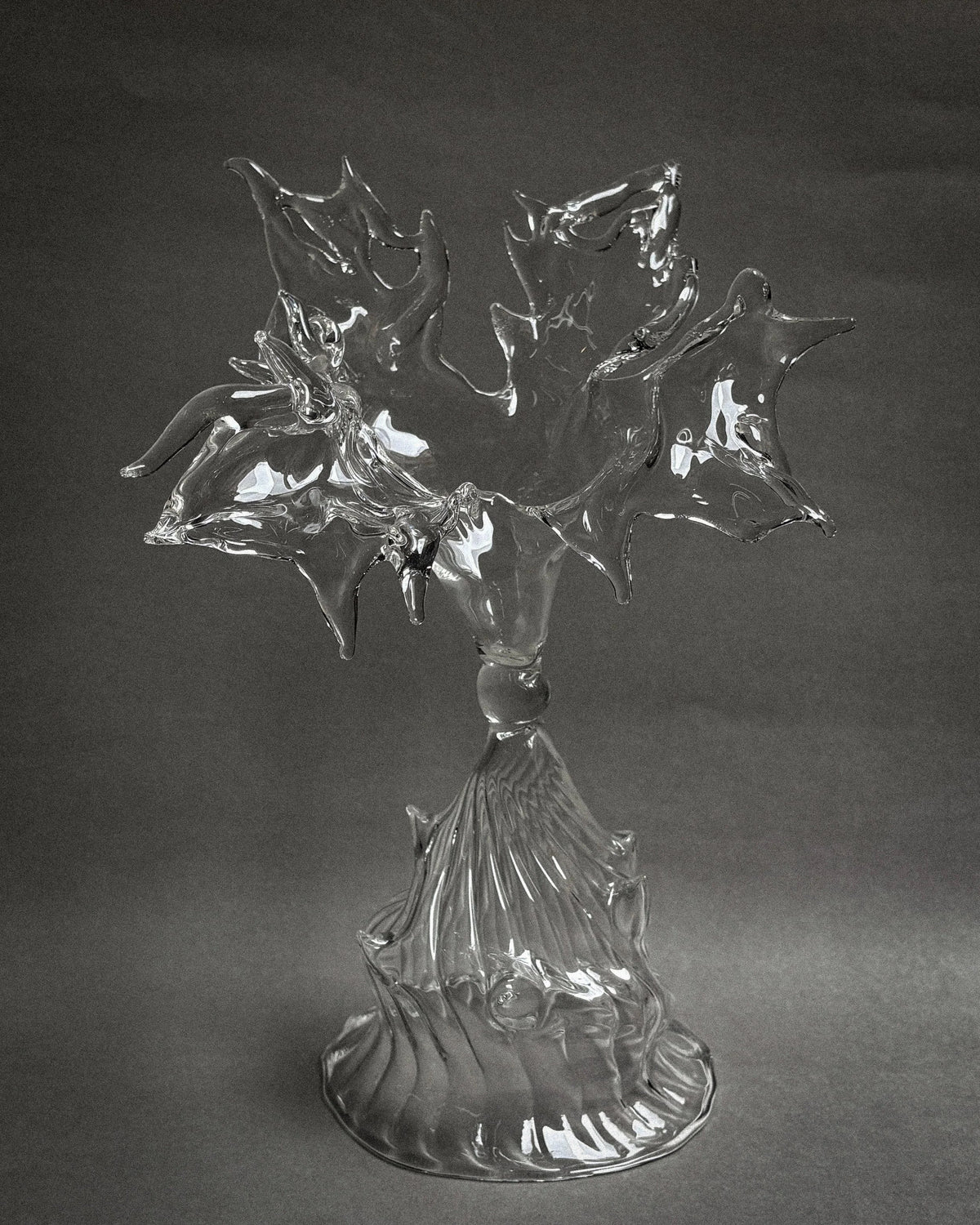 Clear glass sculpture with flowing organic forms on ribbed pedestal base