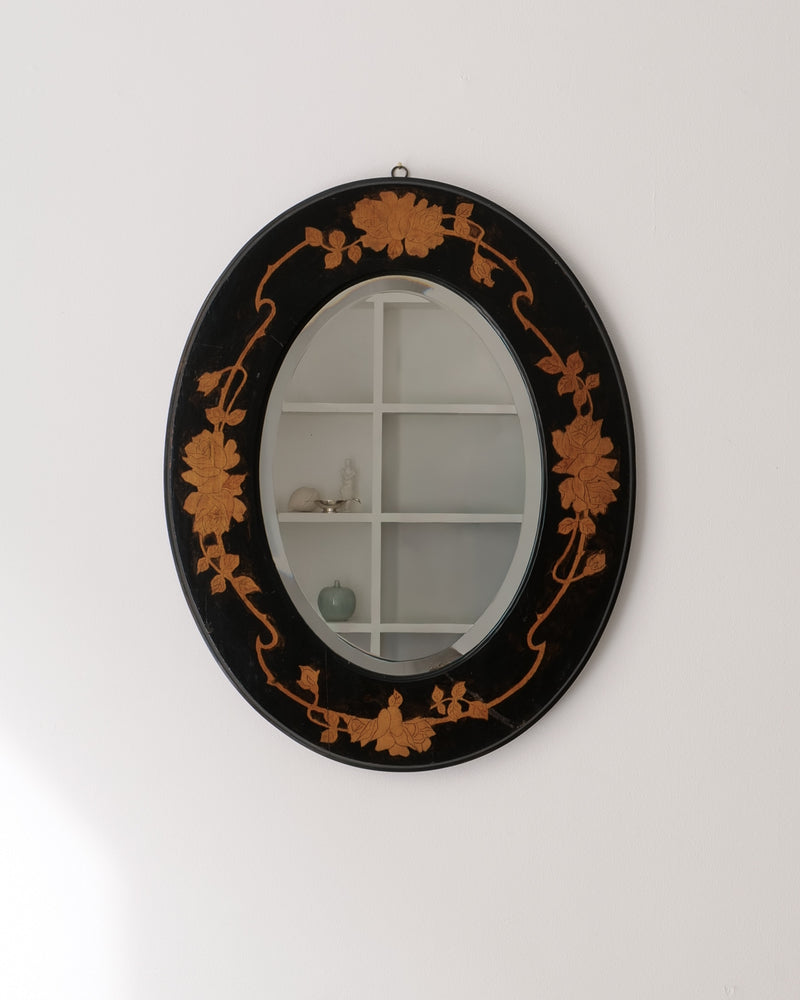 Arts and Crafts oval mirror 1910, black lacquered frame with golden floral marquetry