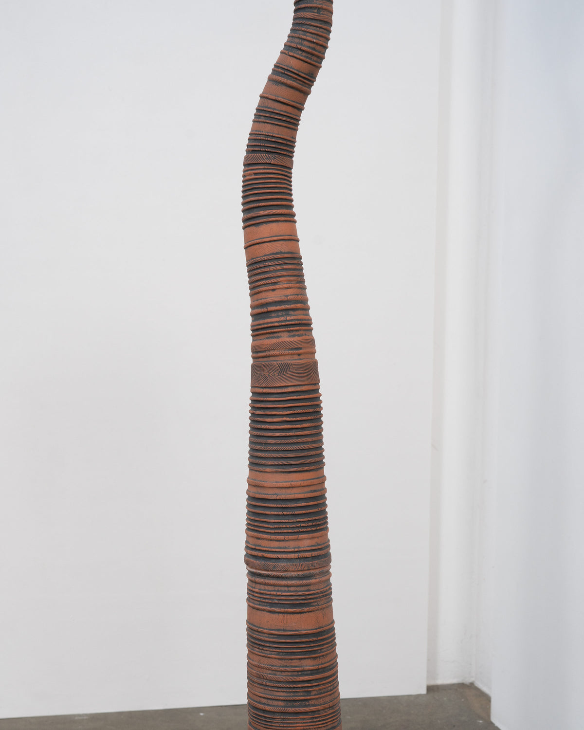 Curved terracotta floor lamp with ribbed texture detail