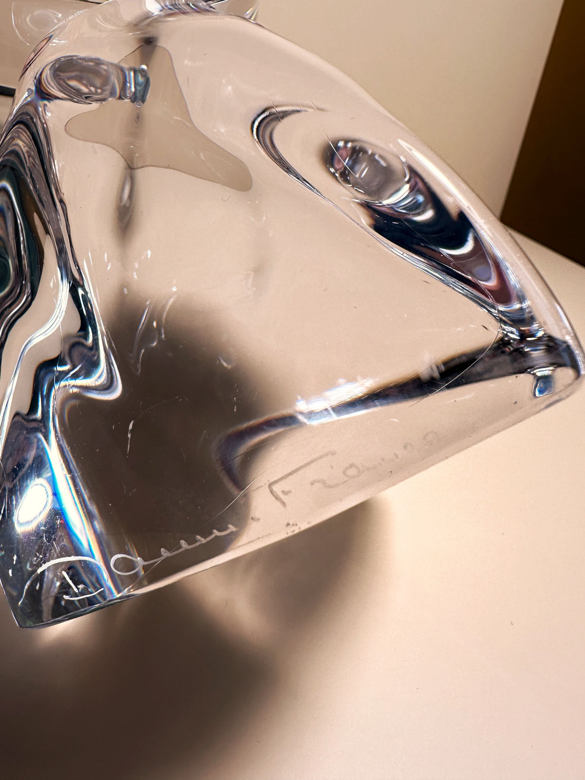 A close-up of the Solid Crystal Glass Brutalist Candelabra by Daum (1950s) from Dodo Vintage, featuring smooth abstract curves and a faint signature along one edge, resting on a light-colored surface.