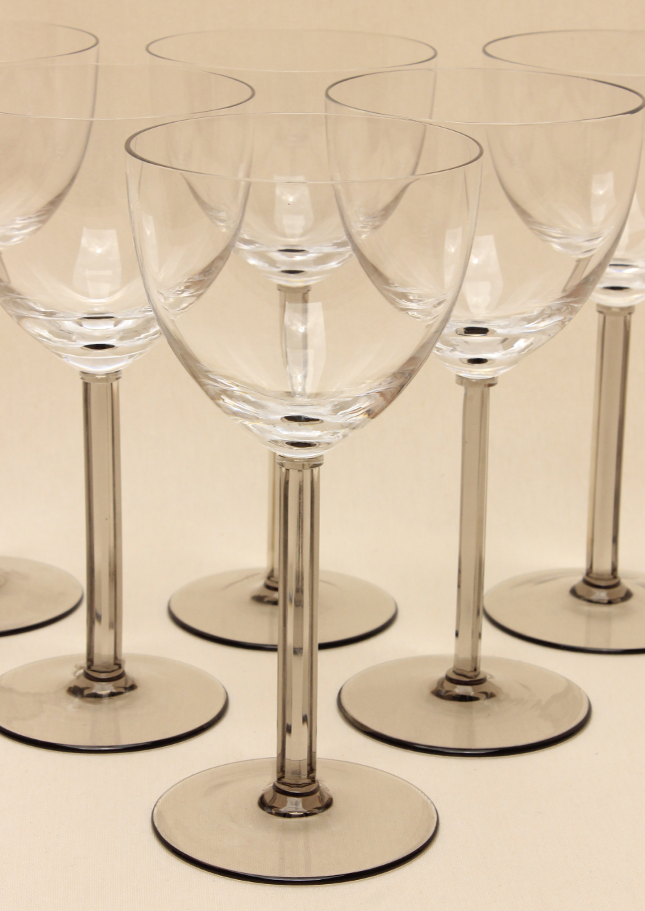 The Crystal Wine Glass Set by Boga Avante Shop features a collection of handcrafted wine glasses with long stems arranged in rows on a light surface, showcasing reflections and transparency that enhance any luxury interior.