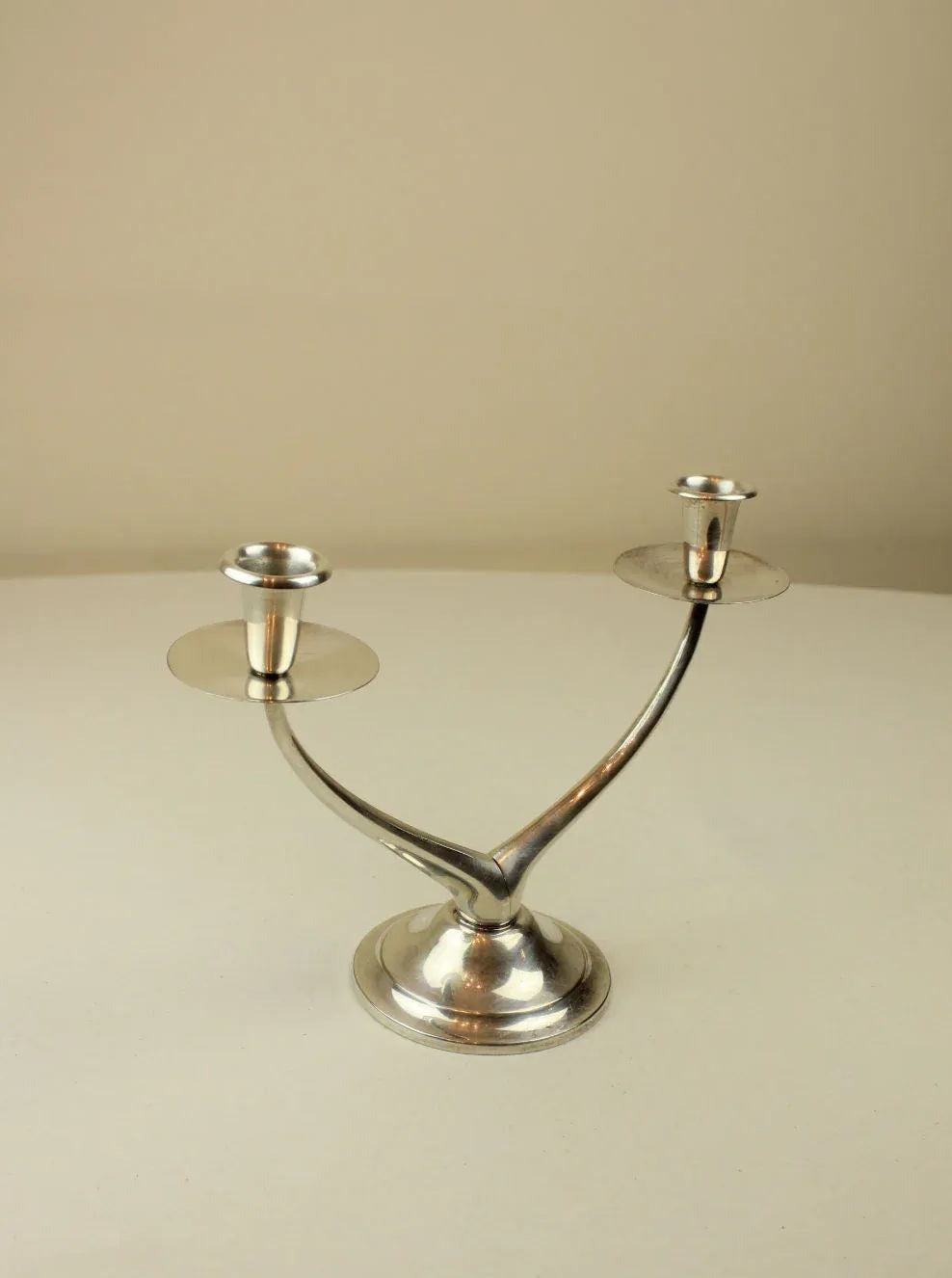Modern black metal wishbone candleholder with brass accents on white background