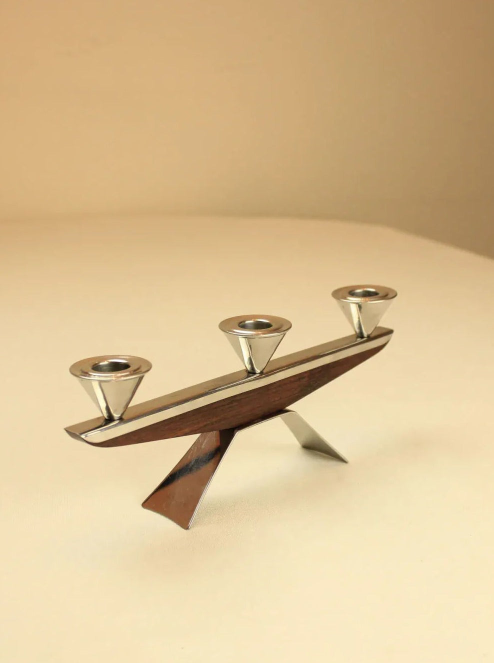 A minimalistic 1960 Candleholder with three chrome-plated metal cups on a wooden, seesaw-like base against a soft beige background by Boga Avante Shop.