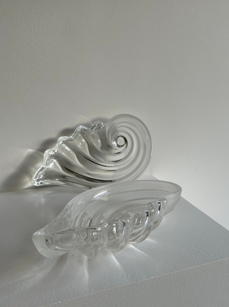 A glass shell butter dish with a clear lid and elegant design sitting on a kitchen countertop