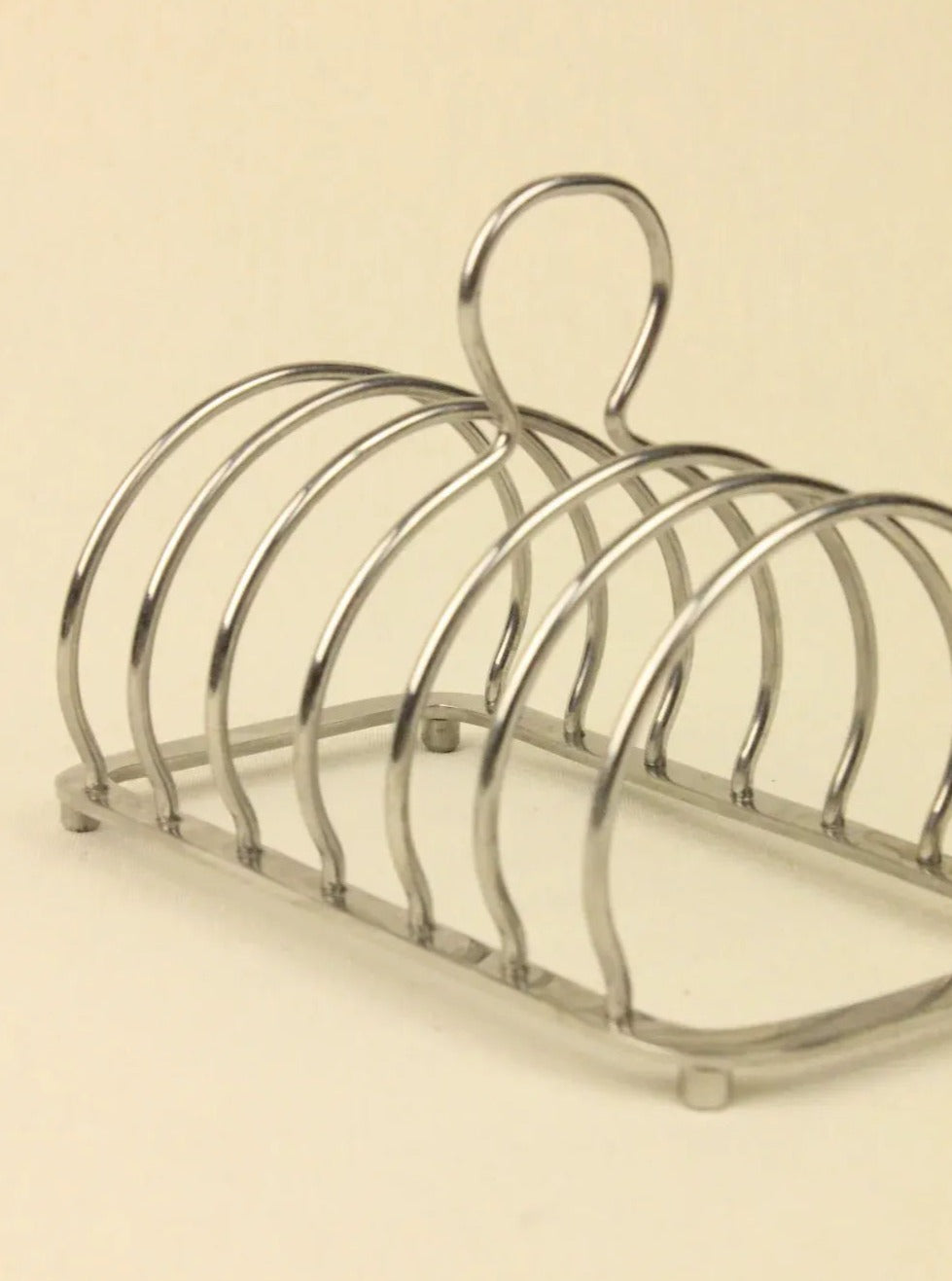 The Boga Avante Shop's Art Deco Toast Holder is a sculptural metal rack with multiple slots, featuring an elegant curved design and a back handle for easy carrying. It's an ideal piece of handcrafted collectible furniture.