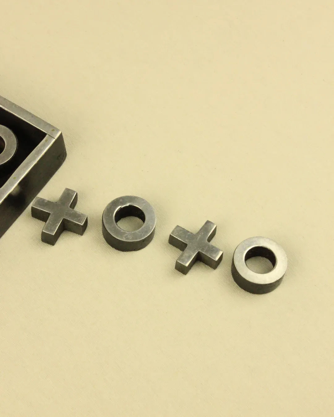 Vintage Boga Avante Shop Tic Tac Toe Game pieces, consisting of x's and o's, are arranged on a plain light beige background.