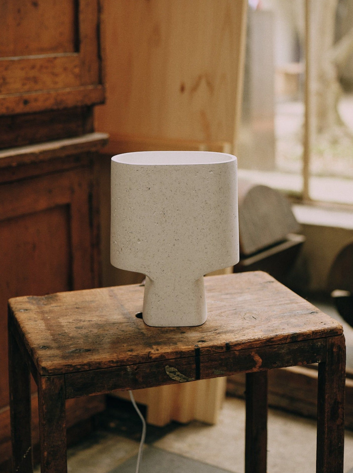 Beautiful Lamp Bien Faite Naturel White casting a warm glow in a minimalist office environment