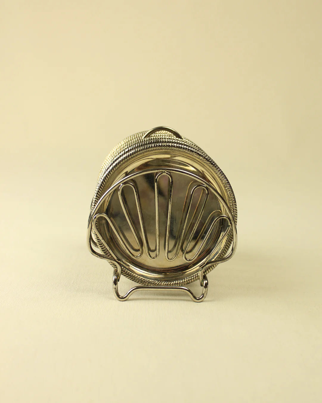 A vintage silver clamshell-shaped purse with Art Nouveau style patterns, standing upright on a light beige background by Boga Avante Shop.