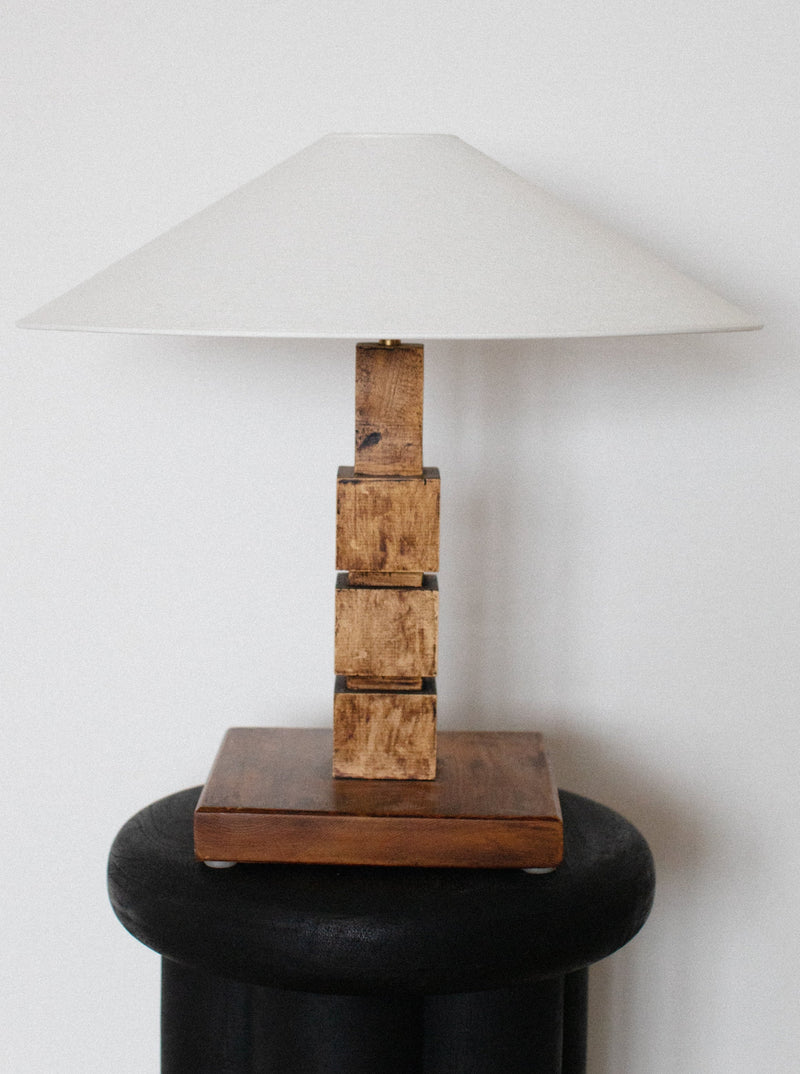Wooden table lamp with a beige fabric shade and carved base
