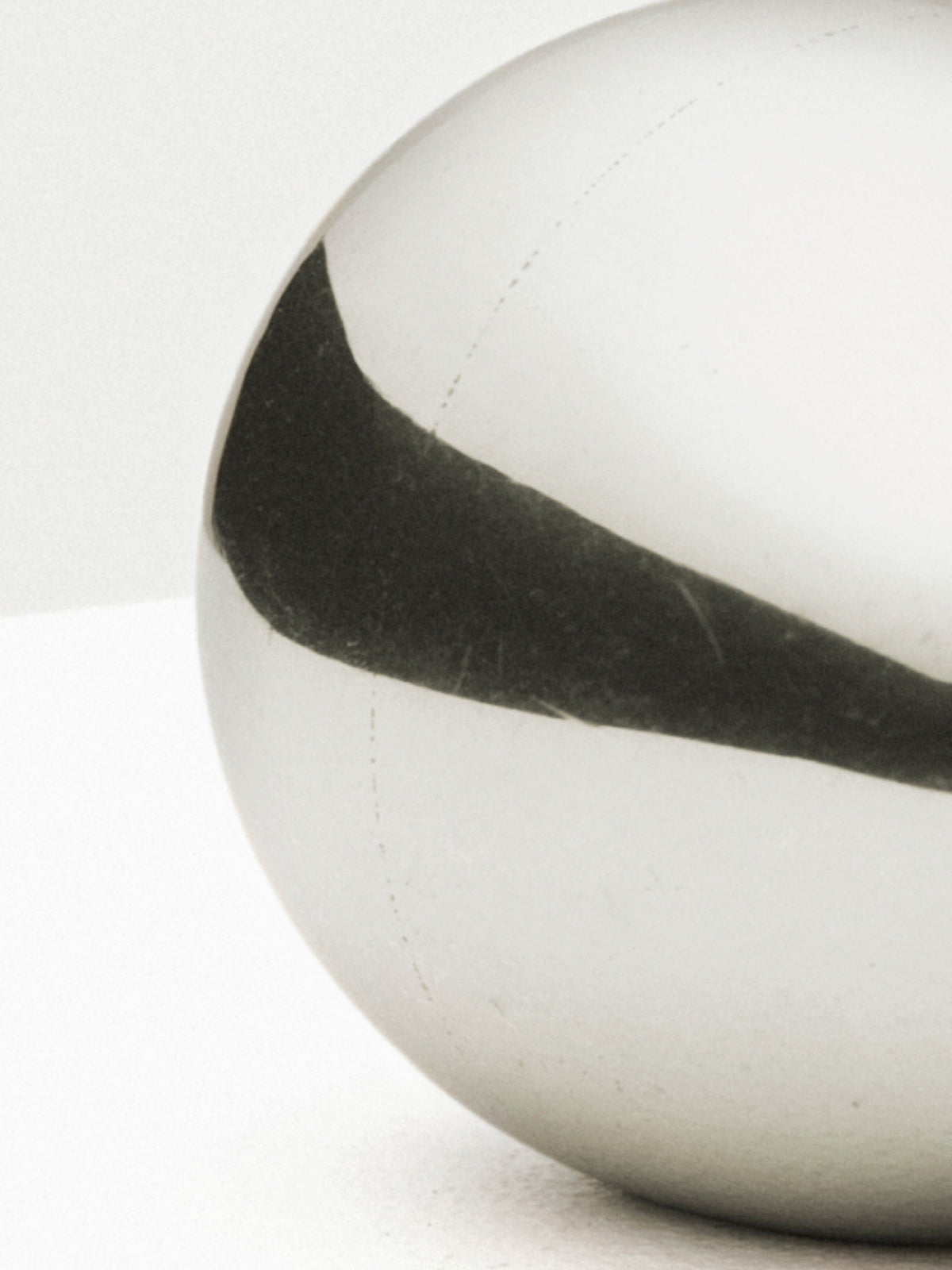 Close-up of a silver egg paperweight with reflection and shadow